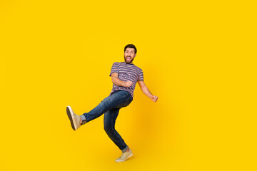Full body length photo of young guy in trendy apparel dancing doing a huge step walk isolated on yellow color background