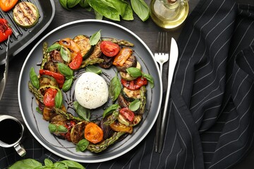 Tasty salad with grilled vegetables and mozzarella cheese served on black wooden table, flat lay