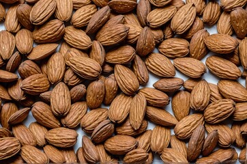 Close-up of a pile of shelled almonds, showing their brown, textured skin and elongated shape