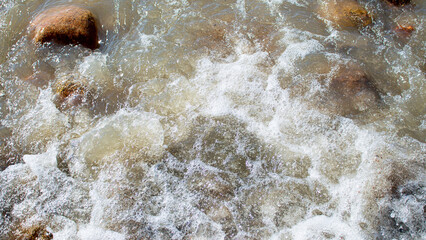 Wild sea, ocean with splashes on  stones. Wave rolls onto shore. Top view, drone. Nature