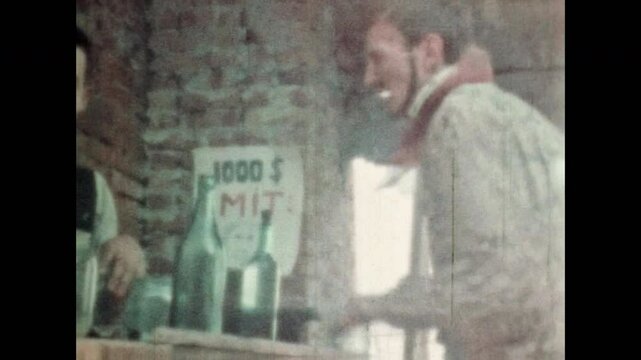 Tired cowboy traveler ordering alcohol in saloon bar. Cinematic parody funny movie comedy of wild west lifestyle. Bartender at rustic tavern counter mixing cocktails. Vintage color film. Retro archive