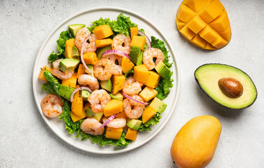 Salad with mango, shrimp and avocado on white plate, top view. 