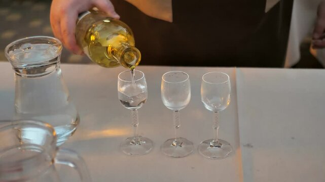 waiter pouring gin from bottle into glass in restaurant. dutch gin. spirit
