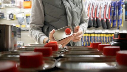 A male buyer choosing a metallic canister of motor oil