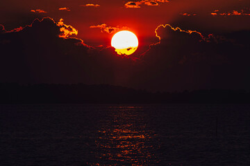 Obraz premium The Fiery Sun Sets as Red Sky Fades to Black