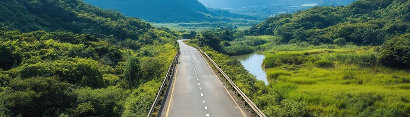 Fototapeta premium Empty winding road through lush green valley with mountains in the distance