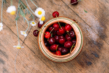 red cherry lies in an old clay pot, village, garden and vegetable garden, harvest, bouquet of daisies, Ukrainian village