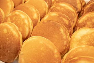 Close-up of neatly arranged golden brown fluffy pancakes on a tray.