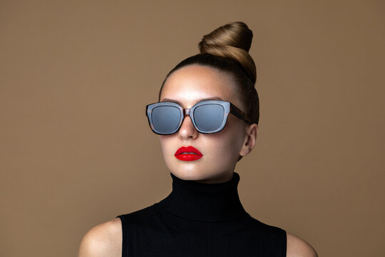 Eye wear fashion. Beauty portrait of glamour model posing in the black square shape classic sunflasses with bold make up.