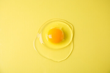 One raw egg on yellow background, top view