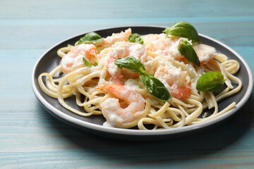 Tasty pasta with shrimps on light blue wooden table, closeup