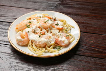 Tasty pasta with shrimps, creamy sauce and cheese on wooden table, closeup