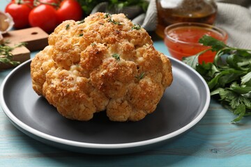 Delicious baked cauliflower and products on light blue wooden table, closeup