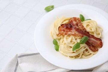 Delicious pasta Carbonara with bacon and basil on white tiled table, closeup