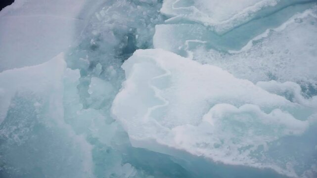 Close-up slow motion of an icebreaker ship breaking through a sheet of ice at the north pole, creating a channel of water