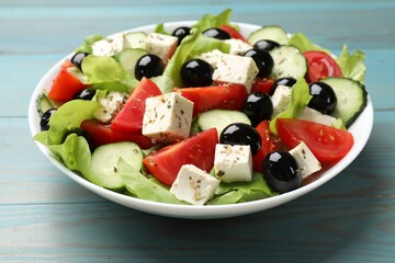 Delicious salad with feta cheese on light blue wooden table, closeup