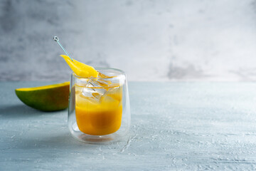 A refreshing glass of mango juice filled with ice and a straw placed on a table