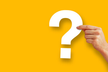 Question mark design. Hand holding a white question mark made of paper on a yellow background.