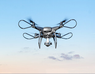 Modern drone with a camera flies in the sky.