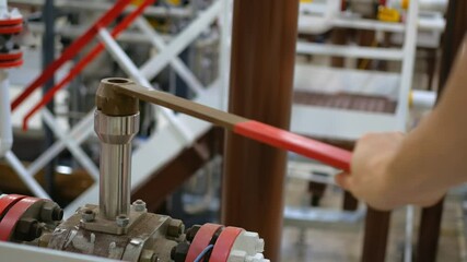 In chemical plant, worker is opening valve to resume flow of chemicals necessary for fertilizer production. operations after scheduled maintenance, production of essential agricultural products.