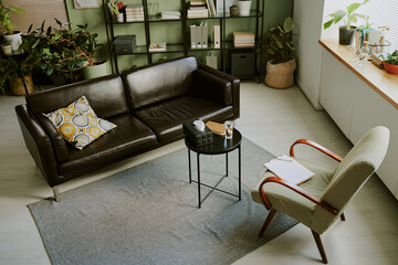 Cozy office lounge area featuring a brown leather couch and an armchair with a side table, indoor...