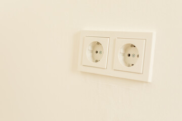 Two white power outlets on a white wall