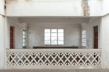 An interior view of an empty room with a decorative white railing and large windows, showcasing...