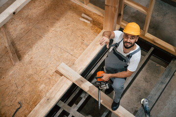 Saw in hands. Industrial worker in wooden warehouse