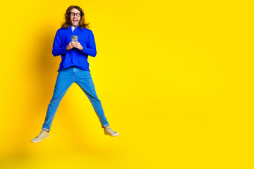 Photo of cheerful glad man wear trendy blue clothes buy credit gadget empty space isolated on yellow color background