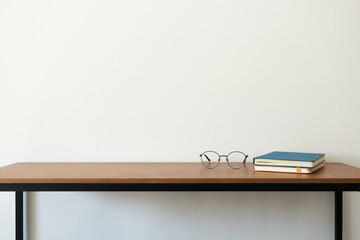 Eyeglasses and books on wooden desk, minimalist interior. Study or back to school concept