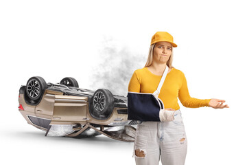 Young female injured passenger with a broken arm wearing an arm splint in front of a car crash