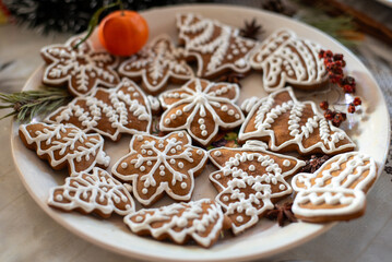Fototapeta premium Gingerbread baked at home oven and painted with sugar glazing. Baking sweets for Christmas holidays at home. Symbolic shapes of Christmas trees and snowflakes. Traditional food for december season.