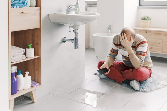 Sad man looking at a water leak