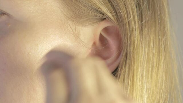 Woman is inserting earplug for hearing protection in her ears.