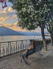 A serene scene of a person sitting next to Lake Como, Italy, enjoying the peaceful waterfront