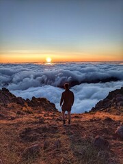 A man watches the sunrise from Pico do Arieiro in Madeira, Portugal, as the clouds form a sea below