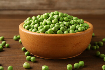 Fresh green peas in bowl on wooden table, closeup