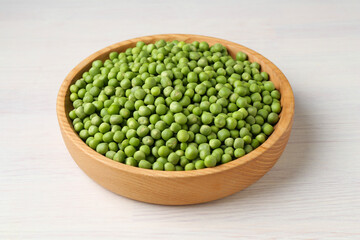 Fresh green peas in bowl on white wooden table, closeup