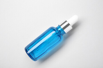 Essential oils in bottle on light background, top view