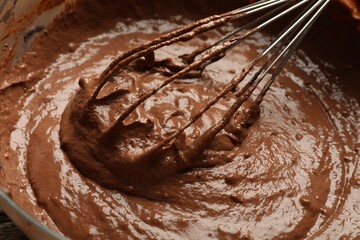 Chocolate dough and whisk in bowl, closeup