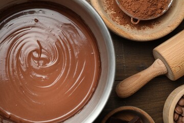 Chocolate dough in bowl and ingredients on wooden table, flat lay
