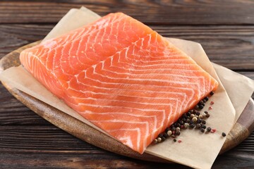 Piece of fresh salmon and spices on wooden table, closeup