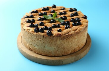 Delicious homemade blueberry pie with mint on light blue background, closeup