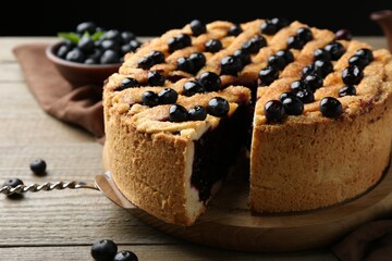 Taking slice of homemade blueberry pie and fresh berries on wooden table, closeup