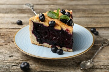 Slice of homemade blueberry pie on wooden table, closeup