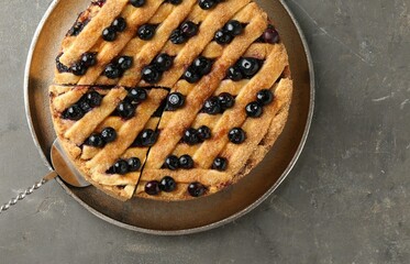 Cut homemade blueberry pie on grey table, top view