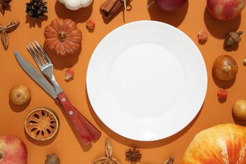 Beautiful table setting with autumn decor on orange background, flat lay