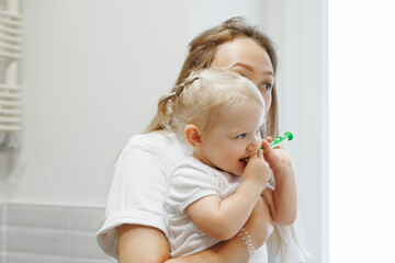 Mother Teaching Her Female Toddler Daughter Cleaning  Her Teeth With Brush At Home Bathroom. Infant Dental Care. Bond Between Parent And Child During Everyday Hygiene Routines