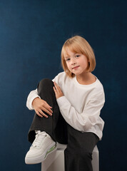 A blonde girl is photographed for a school album in a studio with a movie camera
