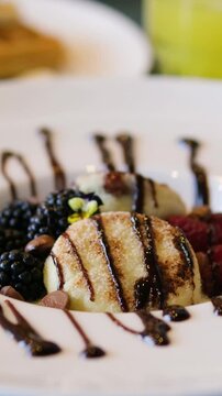 Close up view of syrniki syrniki, cottage cheese pancakes with berries and chocolate cream on white ceramic plate. Delicious healthy breakfast, snack or lunch.